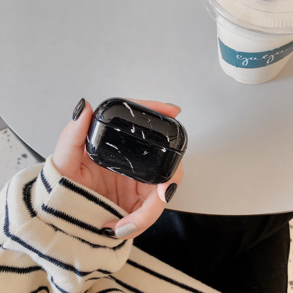 Person holding a black marble-patterned case with a blurred background