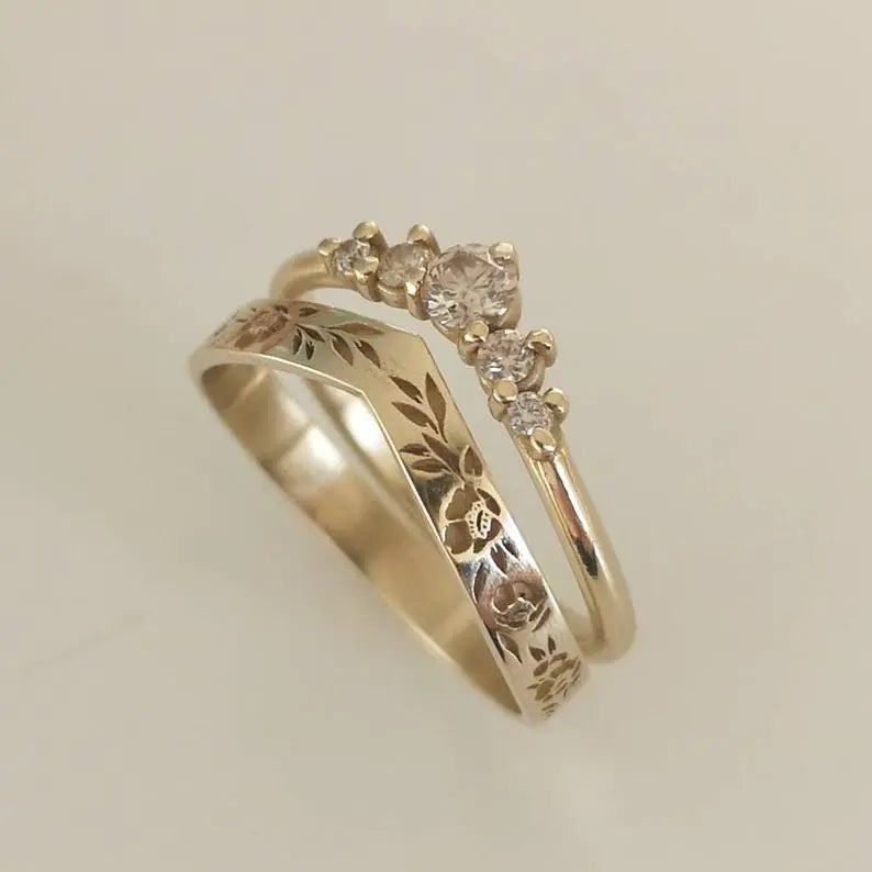Gold ring with floral engraving and small diamonds on a beige background