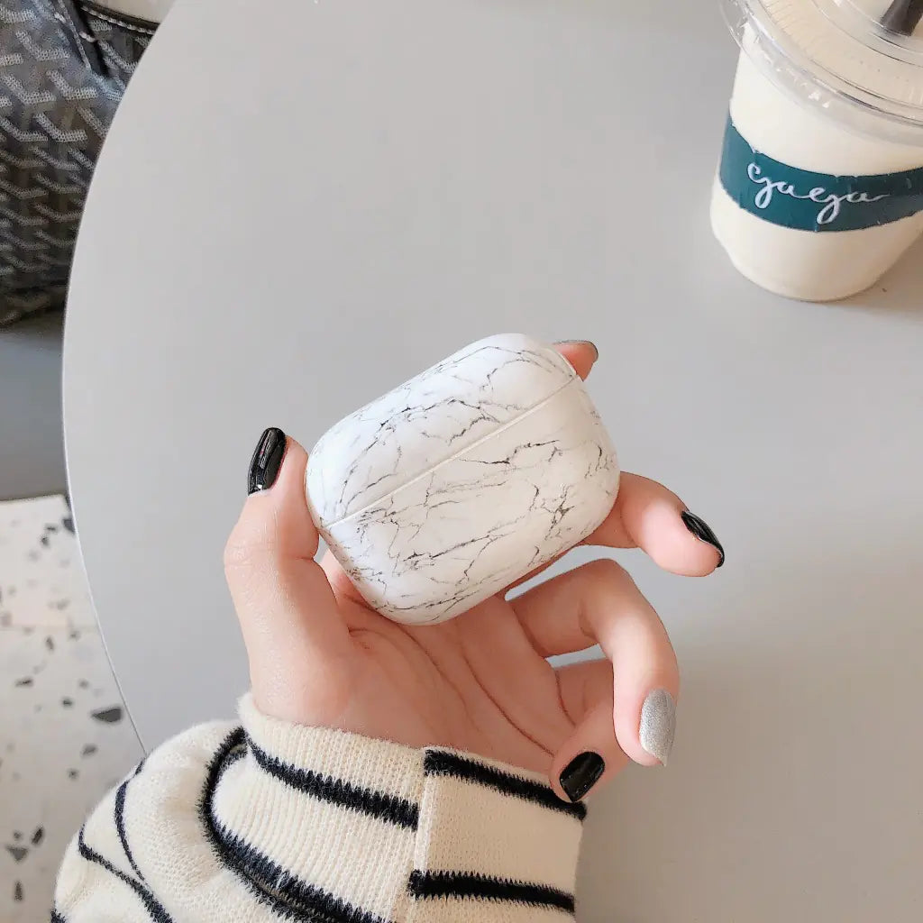 Hand holding a white marble-patterned case with a blurred background