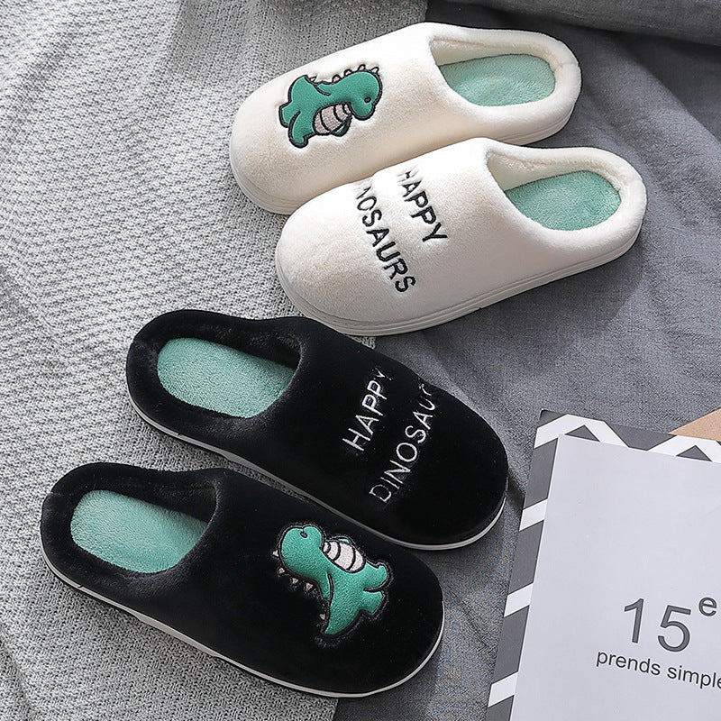 Pair of white and black slippers with dinosaur design on a gray fabric background