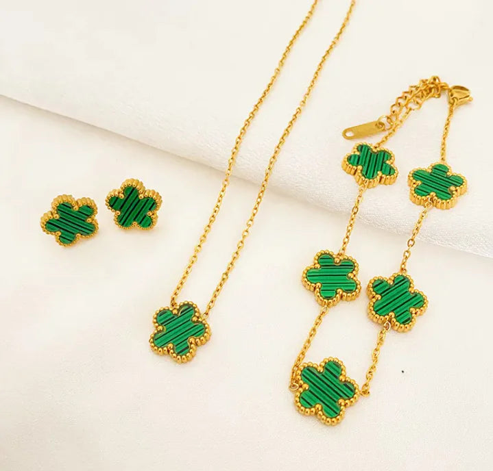 Jewelry set with green clover-shaped pendants on gold chains.