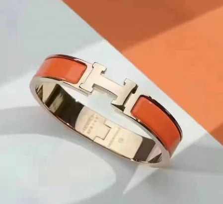 Bracelet with orange band and gold clasp on a light background