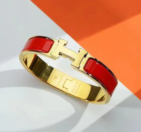 Gold bracelet with red accents on a white and orange background
