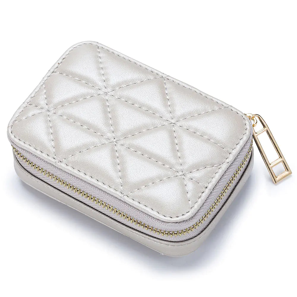 Quilted white jewelry case with gold zipper on a white background