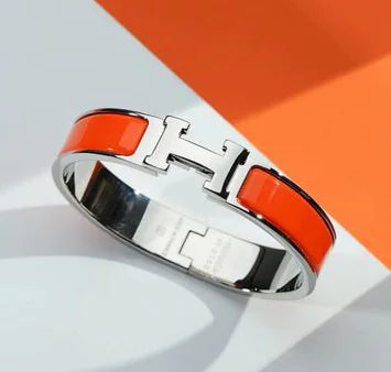 Silver bracelet with orange band on a white and orange background