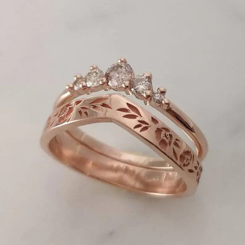 Rose gold ring with diamond accents on a light gray background