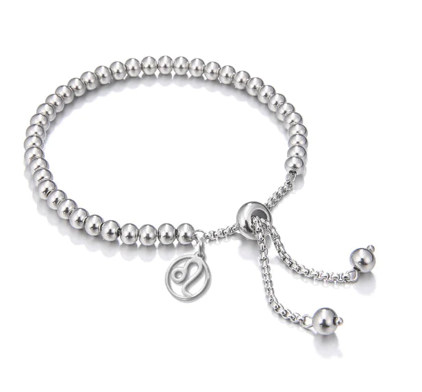 Silver beaded bracelet with a chain and round charm on a white background