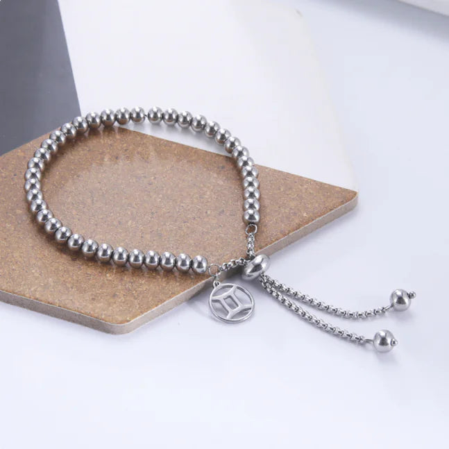 Silver beaded bracelet with a charm on a white background
