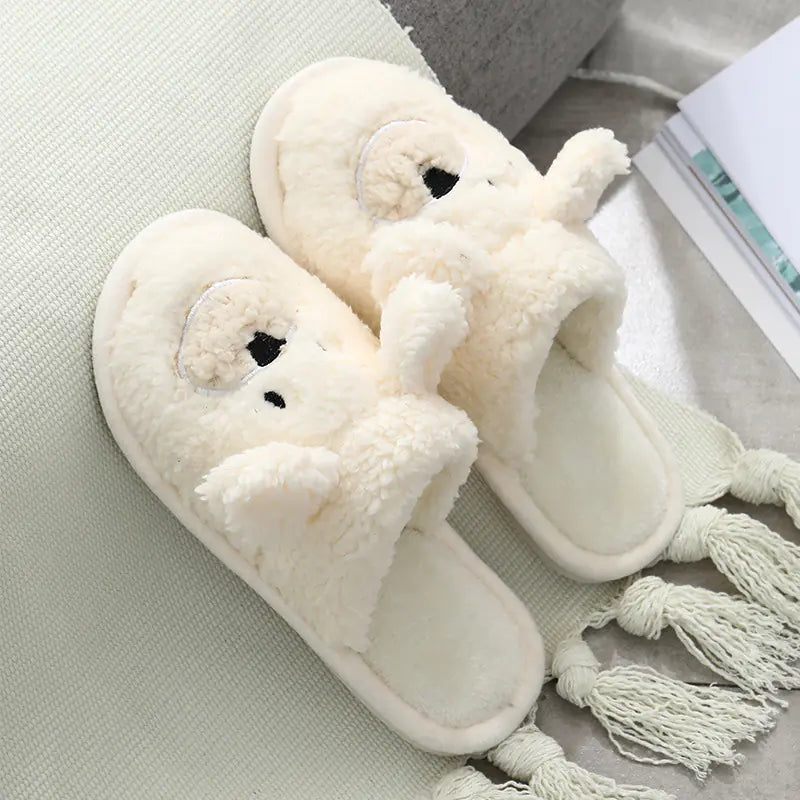 Pair of white slippers with bear faces on a light surface