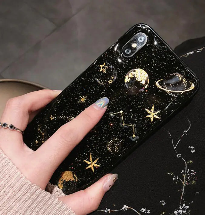 Phone case with celestial designs held by a hand on a dark background