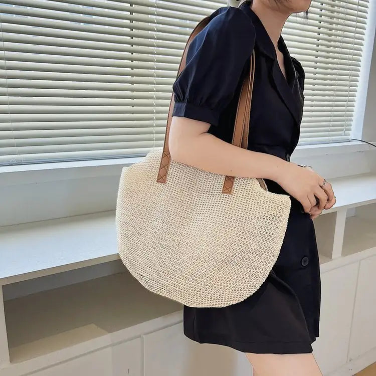 Person holding a woven beige bag indoors with a neutral background