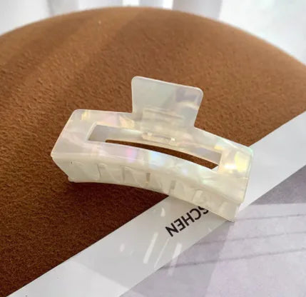 Clear hair clip on a brown surface with a white label
