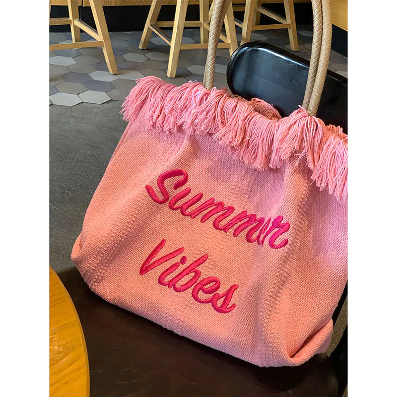 Pink tote bag with 'Summer Vibes' text on a table indoors