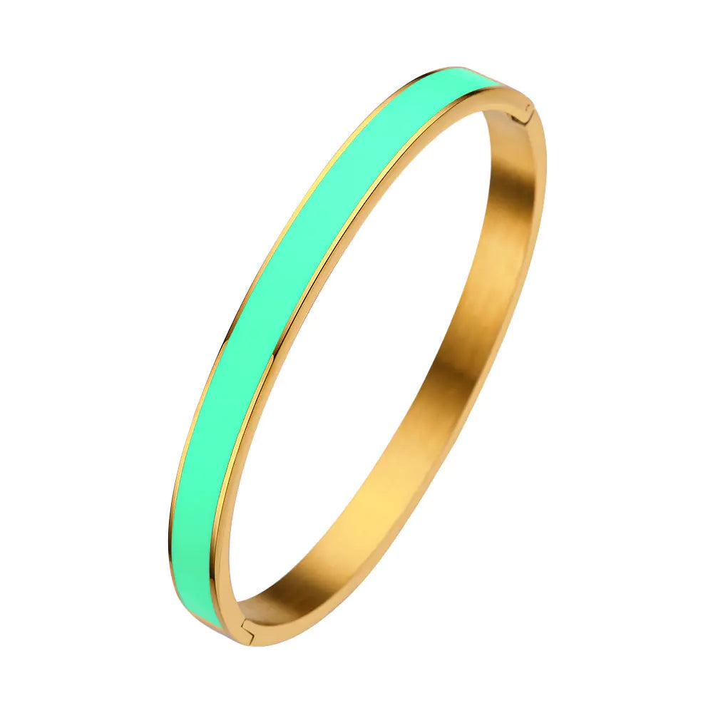 Gold bangle with a green interior on a white background