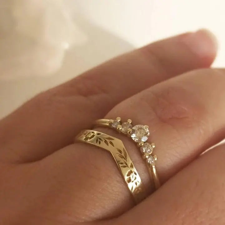 Close-up of a hand wearing two gold rings with diamond accents.