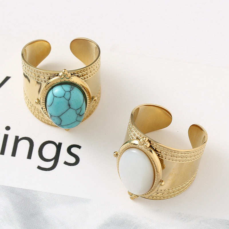 Two gold cuff bracelets with turquoise and white stones on a white background