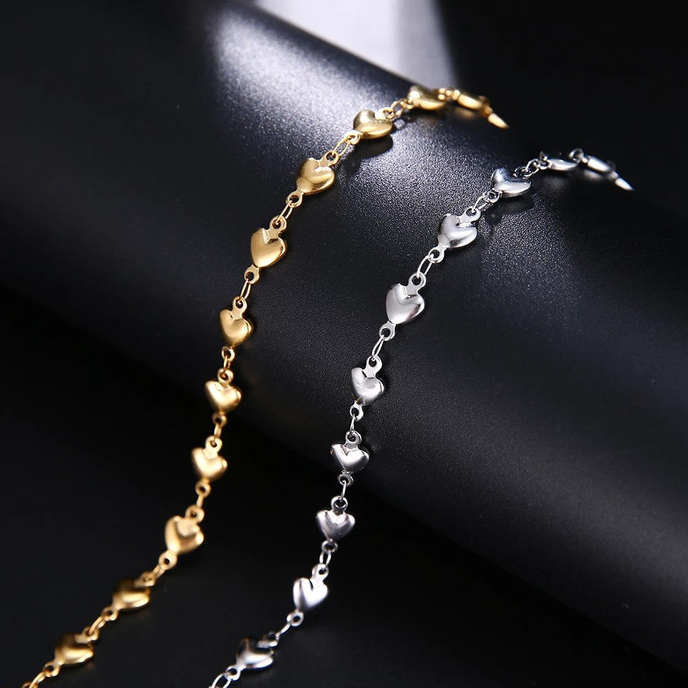 Gold and silver heart-shaped chain necklaces on a dark surface