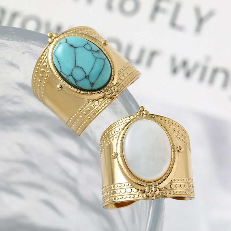Gold cuffs with turquoise and white stones on a light background