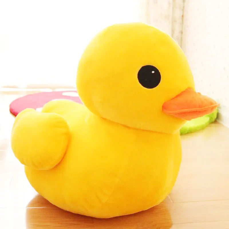 Yellow plush duck toy on a wooden surface with a light-colored background