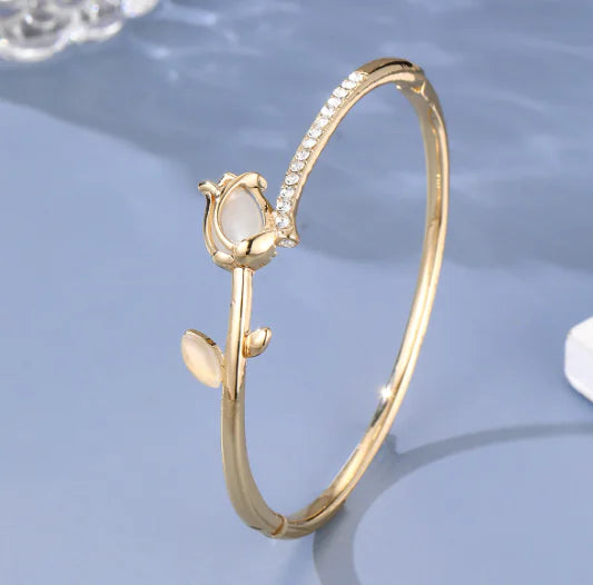 Gold bracelet with a central stone on a light blue background