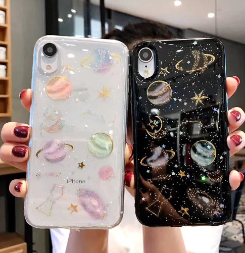 Two phone cases with celestial designs held by a person.