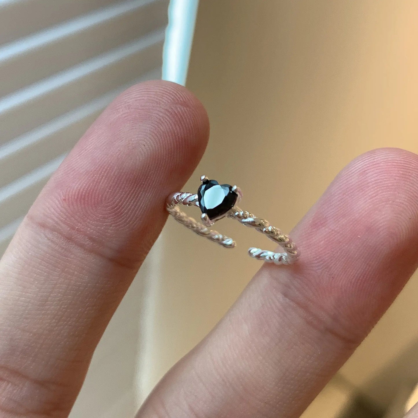 Sterling-silver twist ring with black zirconia centre stone resting between fingers.