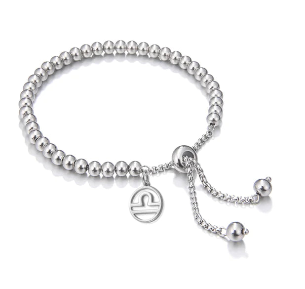 Silver beaded bracelet with a heart charm on a white background