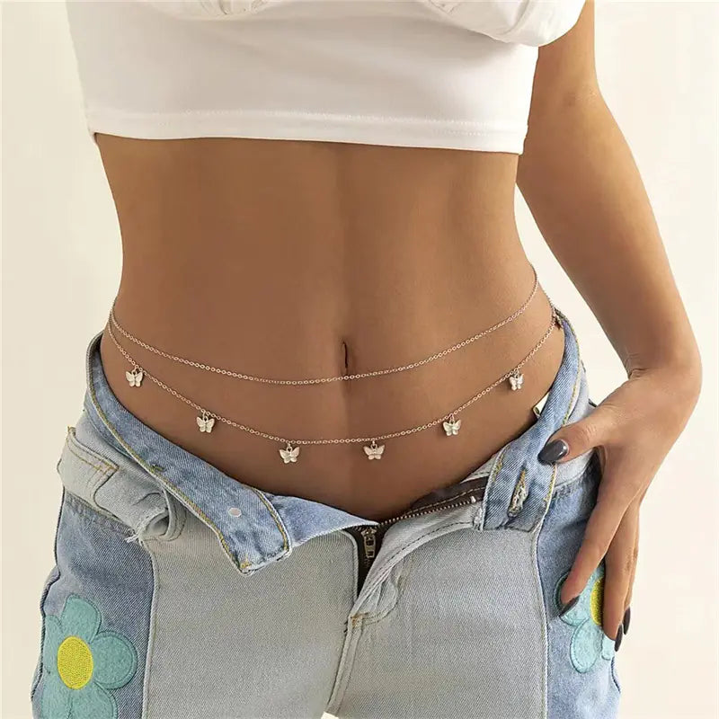 Person wearing a gold chain belt with floral designs on a plain background