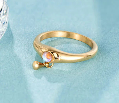 Gold ring with a small gemstone on a light blue background