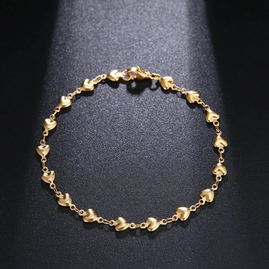 Gold bracelet with heart-shaped links on a dark background