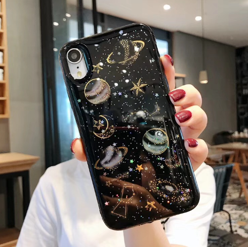 Person holding a phone case with celestial design in an indoor setting