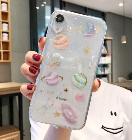 Phone case with celestial designs held by a person indoors.