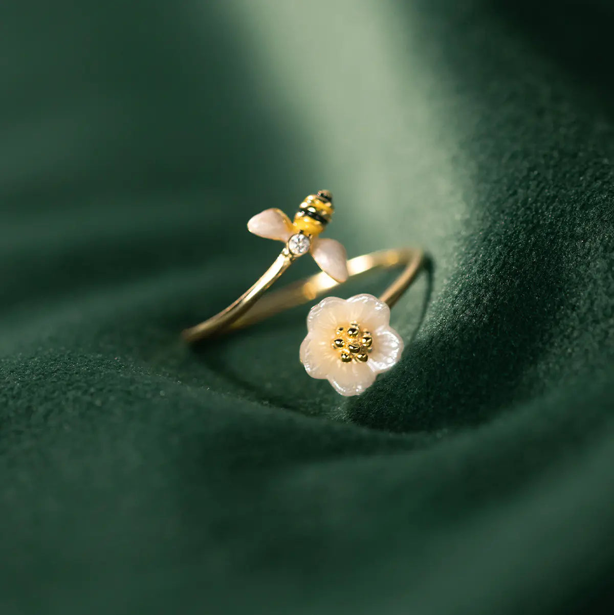 Delicate gold ring with floral design on a green fabric background