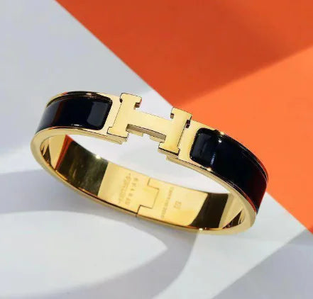 Gold bracelet with black stones on a white and orange background