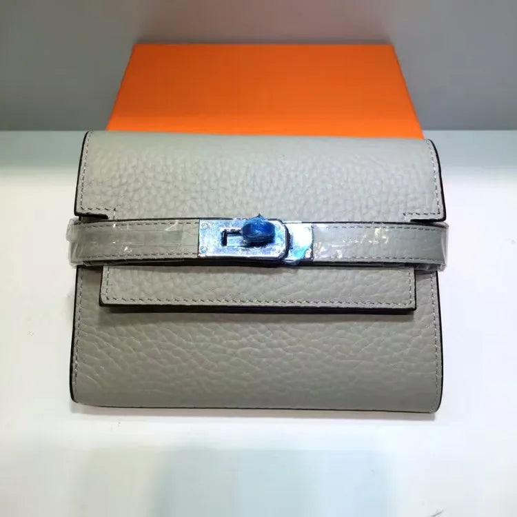 Gray textured handbag with a blue flower clasp on an orange background