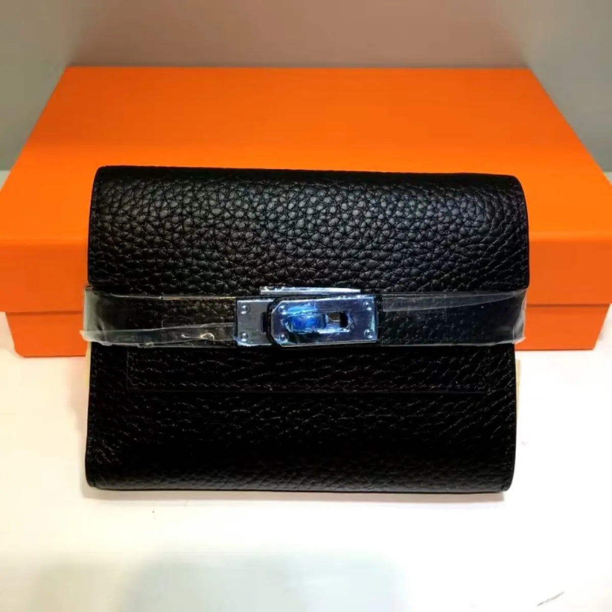 Black textured wallet with a blue clasp on an orange box background