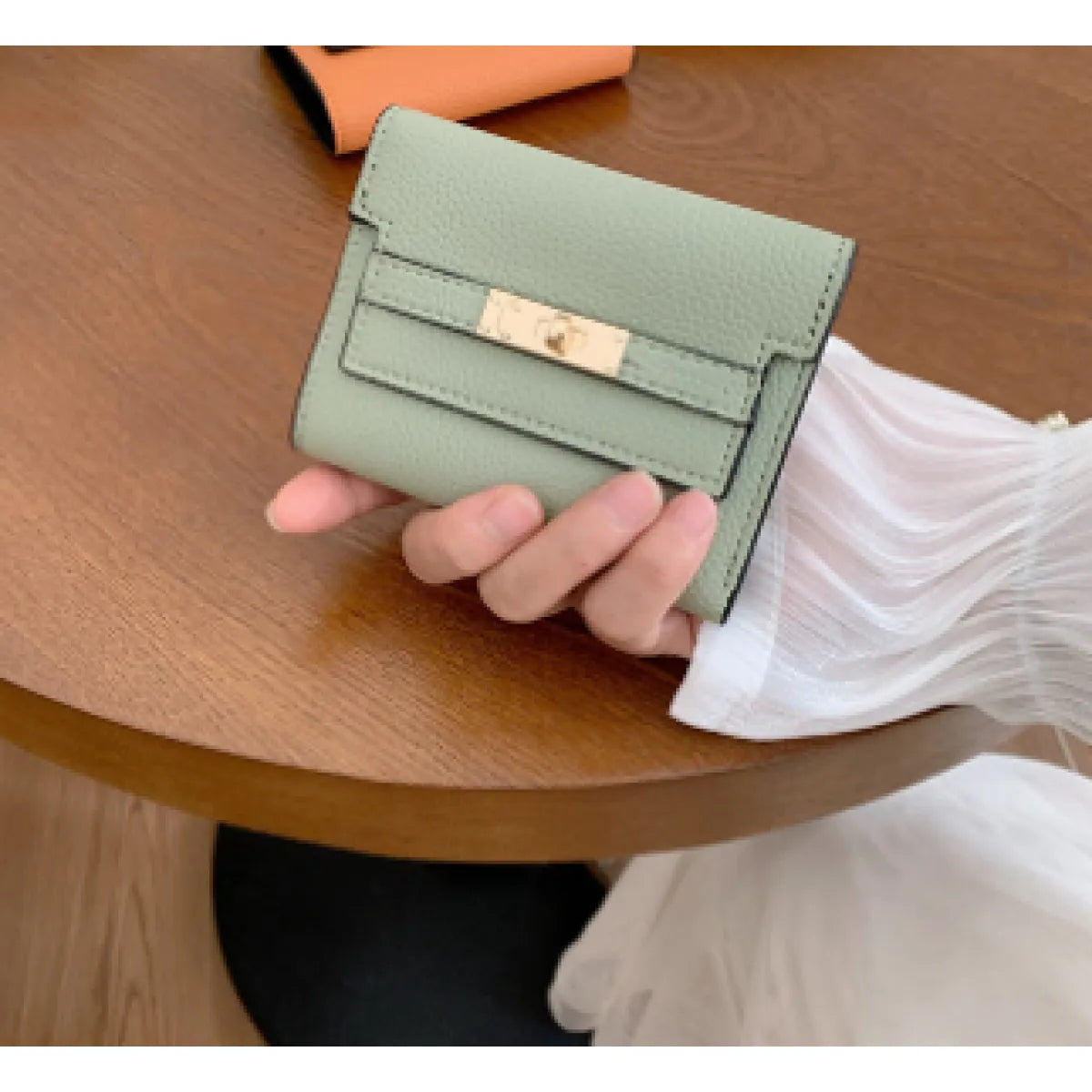 Green wallet held by a hand on a wooden surface