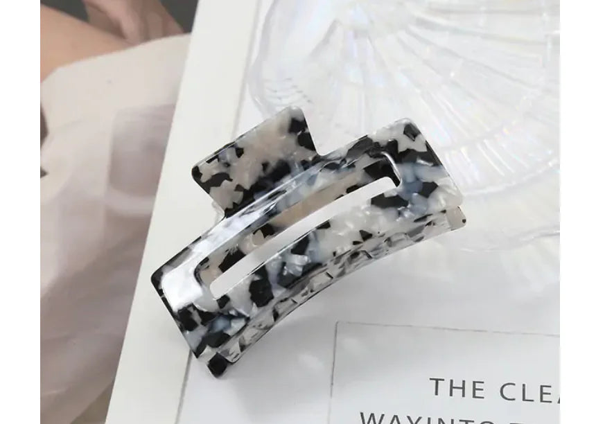 Black and white patterned hair clip on a white surface with text