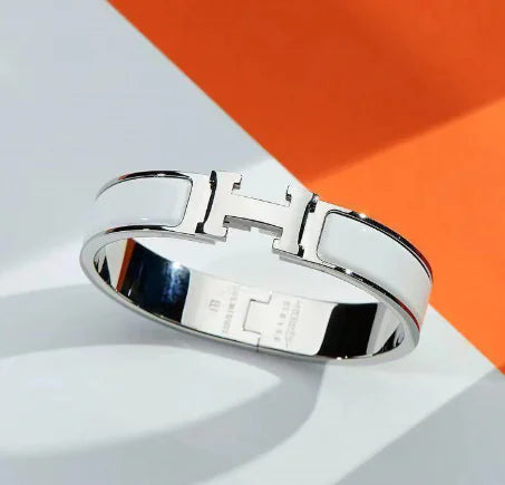 Silver bracelet with a prominent logo on a white and orange background