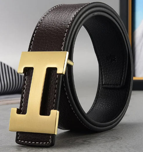 Black leather belt with a gold H-shaped buckle on a gray surface.