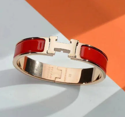 Bracelet with red band and gold clasp on a light background