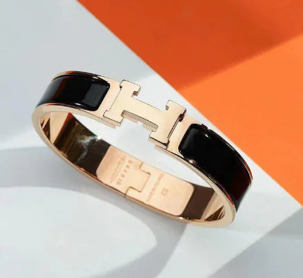 Rose gold and black enamel bracelet on a white and orange background