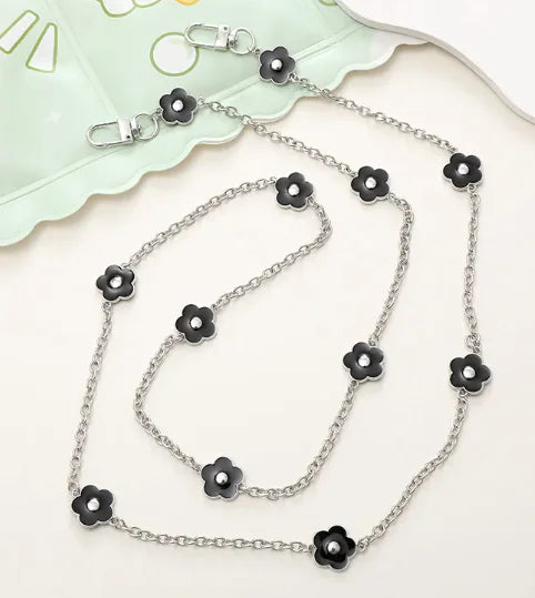 Silver chain necklace with black flower pendants on a white background