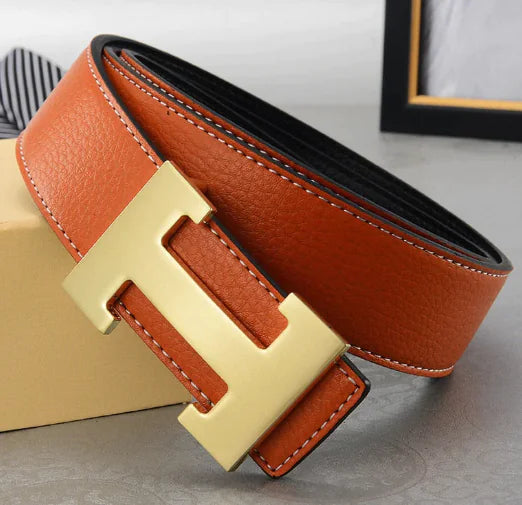 Brown leather belt with gold buckle on a light gray surface