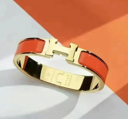 Gold bracelet with red accents on a white and orange background