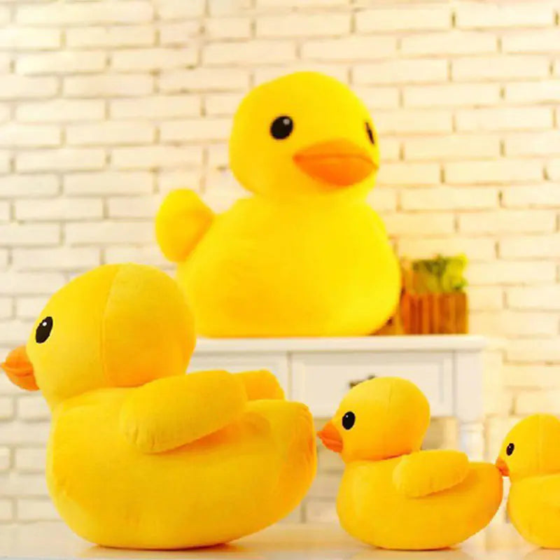 Four yellow rubber duck plush toys on a light wooden surface with a brick wall background.