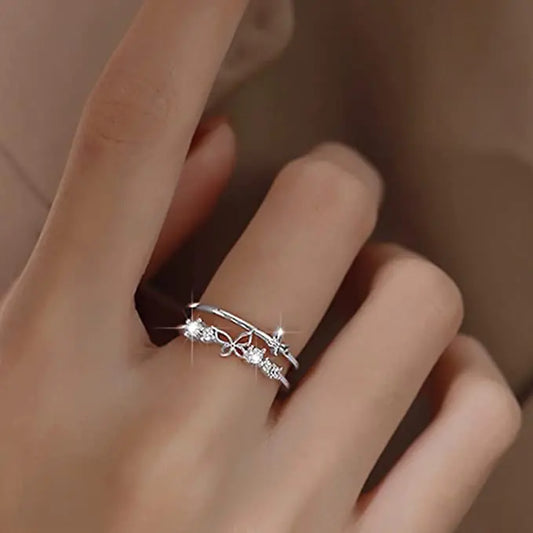 Silver ring with intricate design on a person's finger against a neutral background