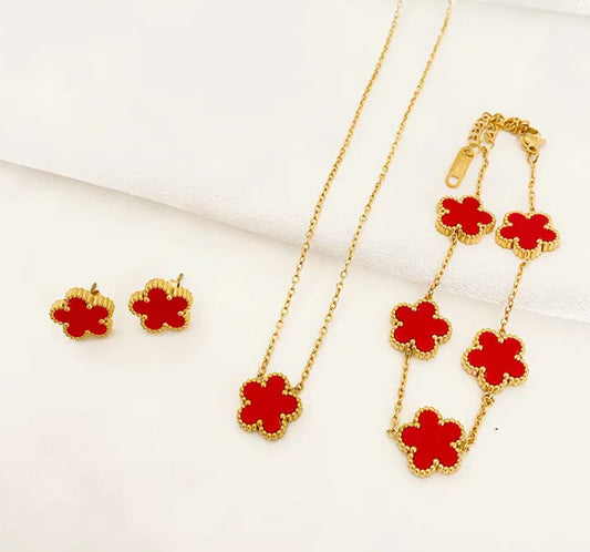 Jewelry set with red flower-shaped pendants on gold chains against a white background