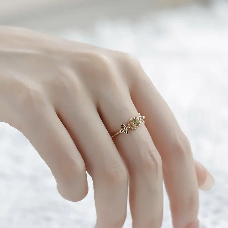 Delicate ring with a green gemstone on a hand against a soft background