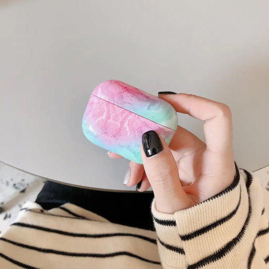 Hand holding a colorful airpod case against a neutral background